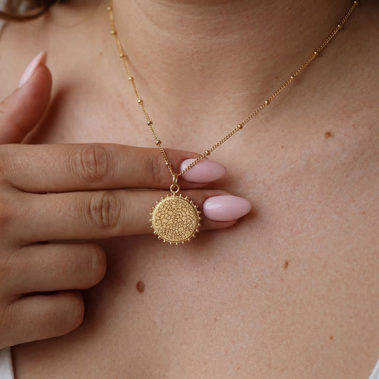 Goldene Kette mit Nasenabdruck-Anhänger, in der Hand gehalten