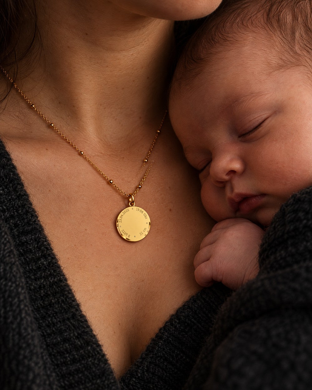 Mother with a sleeping newborn against her chest, wearing a Mizodia necklace with birth details engraving
